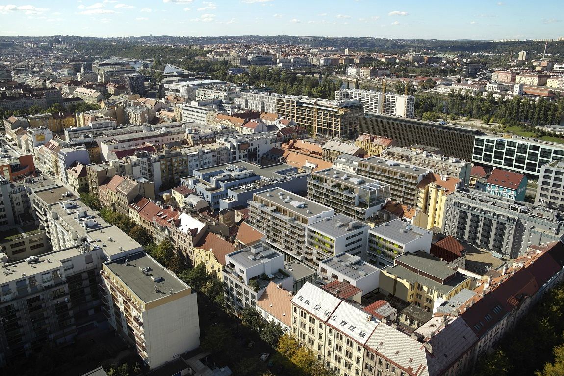 Letecký pohled na Karlín — bloky činžovních domů, ploché i sedlové střechy, v pozadí zeleň Vítkova